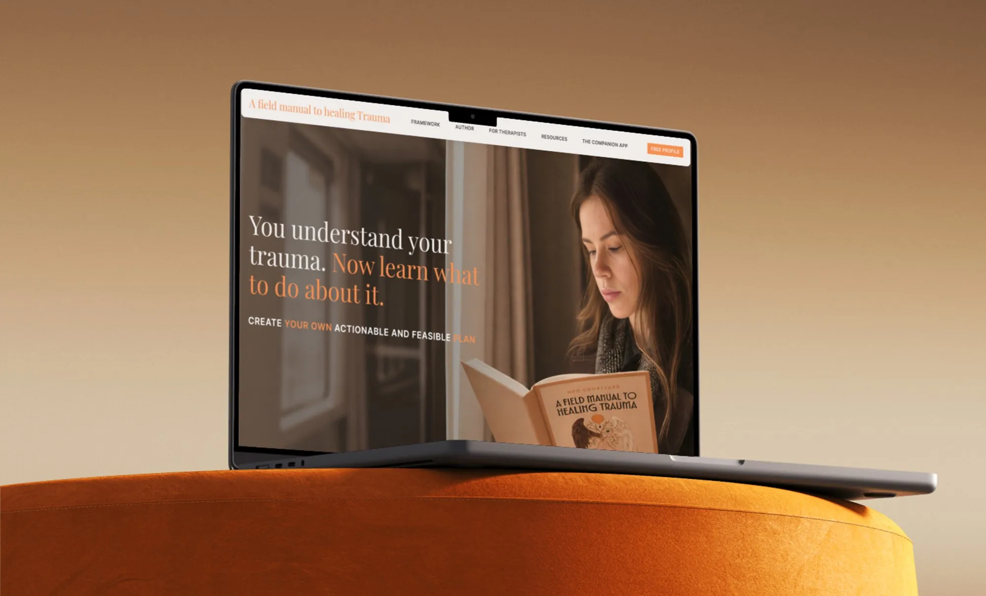 Laptop on an orange velvet seat showing the Neo Courtyard homepage: “You understand your trauma. Now learn what to do about it.”